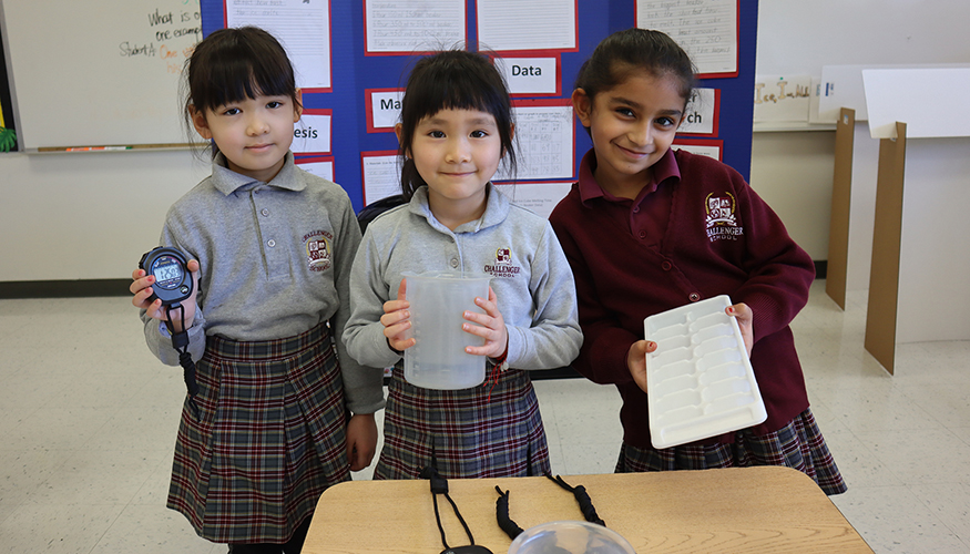 Three smiling Challenger students presenting their Science Fair project